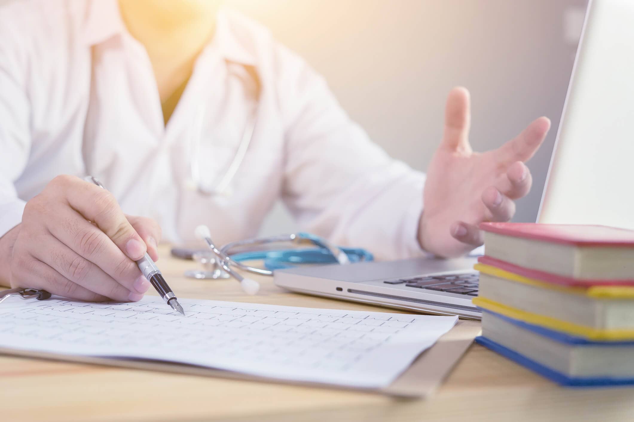 gesturing hands of healathcare professional near stack of books