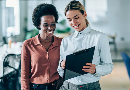 Woman showing another woman something on a clipboard
