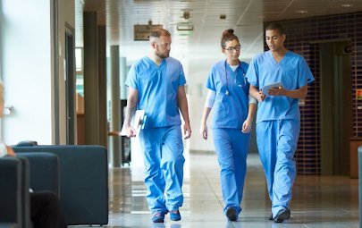 two male nurses and a female nurse walking down a hall two male nurses and a female nurse walking down a hall