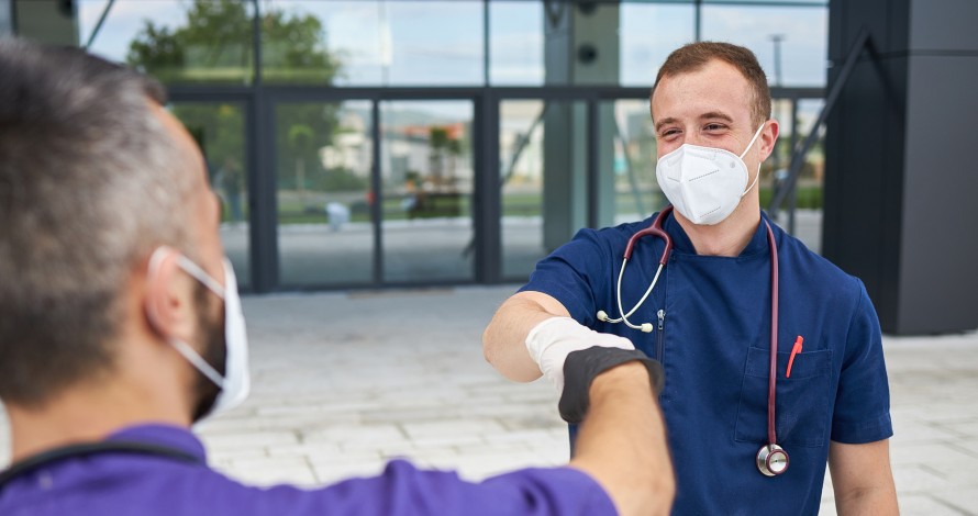 travel nurse fist bumping a fellow nurse outside of hospital travel nurse fist bumping a fellow nurse outside of hospital