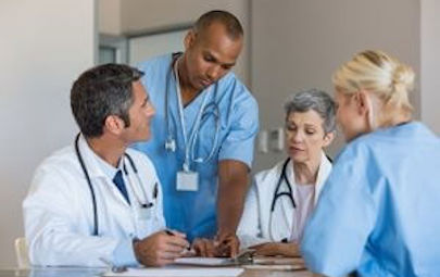 four healthcare professionals around a table collaborating four healthcare professionals around a table collaborating