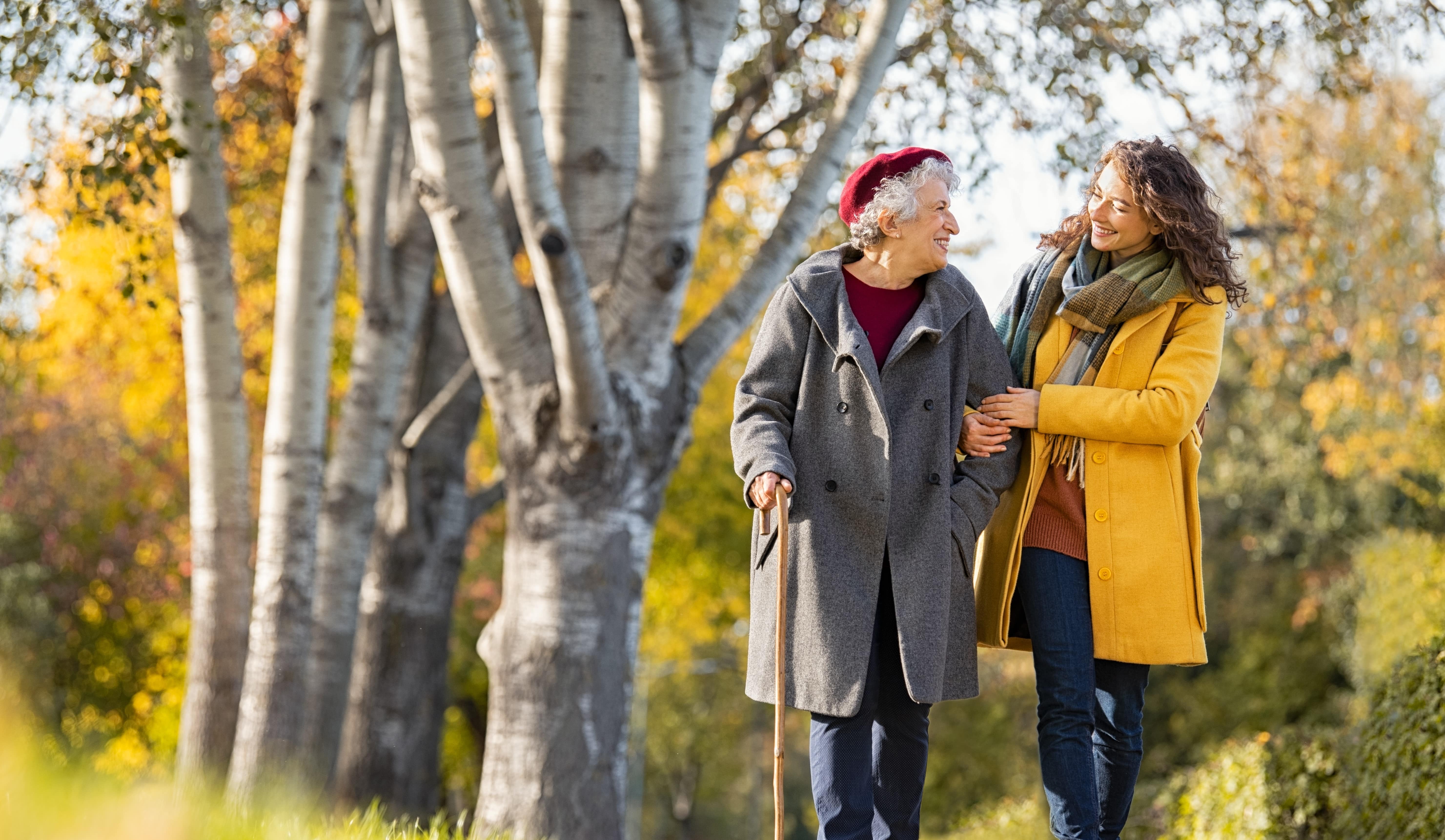 woman and caregiver walking through park