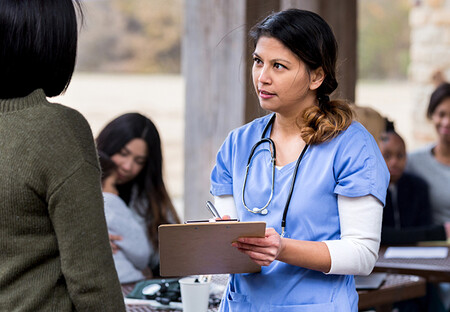 Nurse with clipboard listening to patient