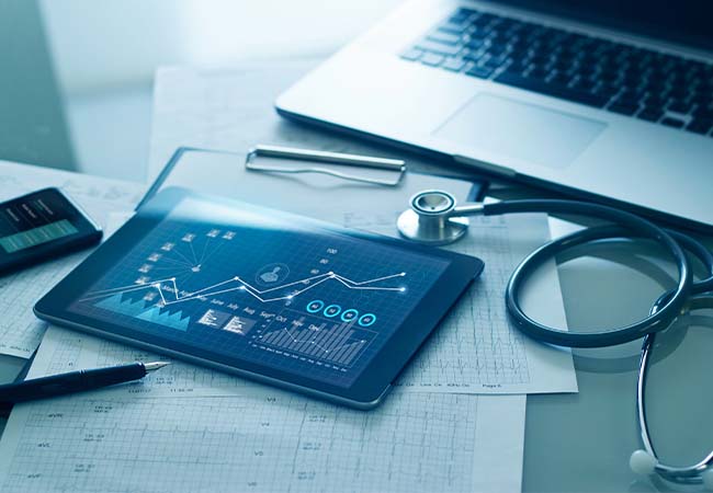 Physician's desk with laptop, table computer, and documents